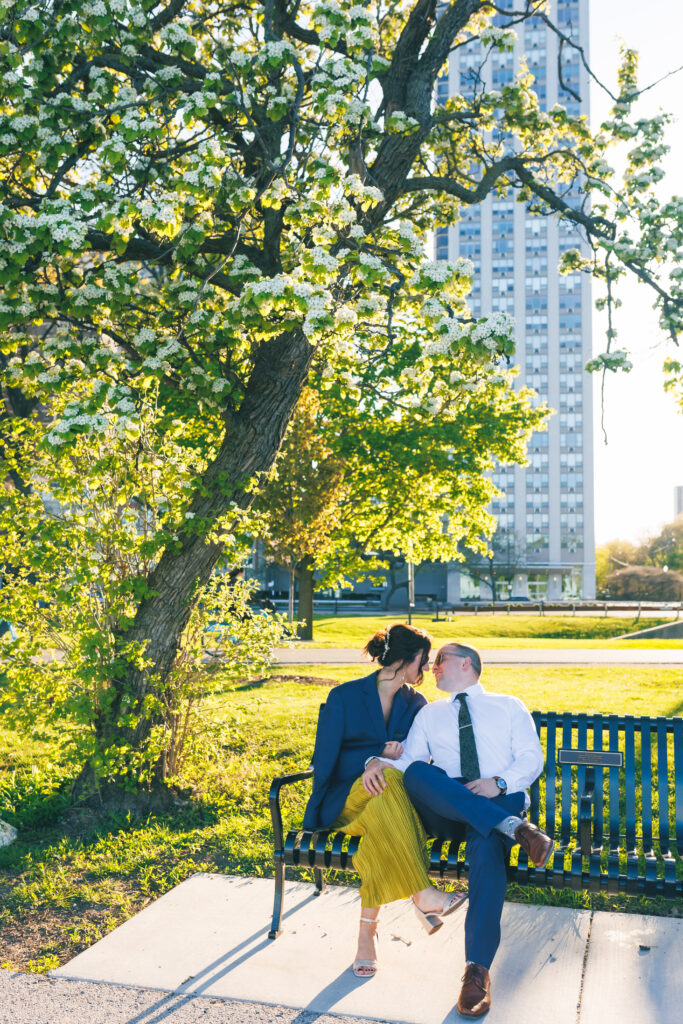 Chicago engagement session in Gold Coast with couple laughing on a park bench during golden hour