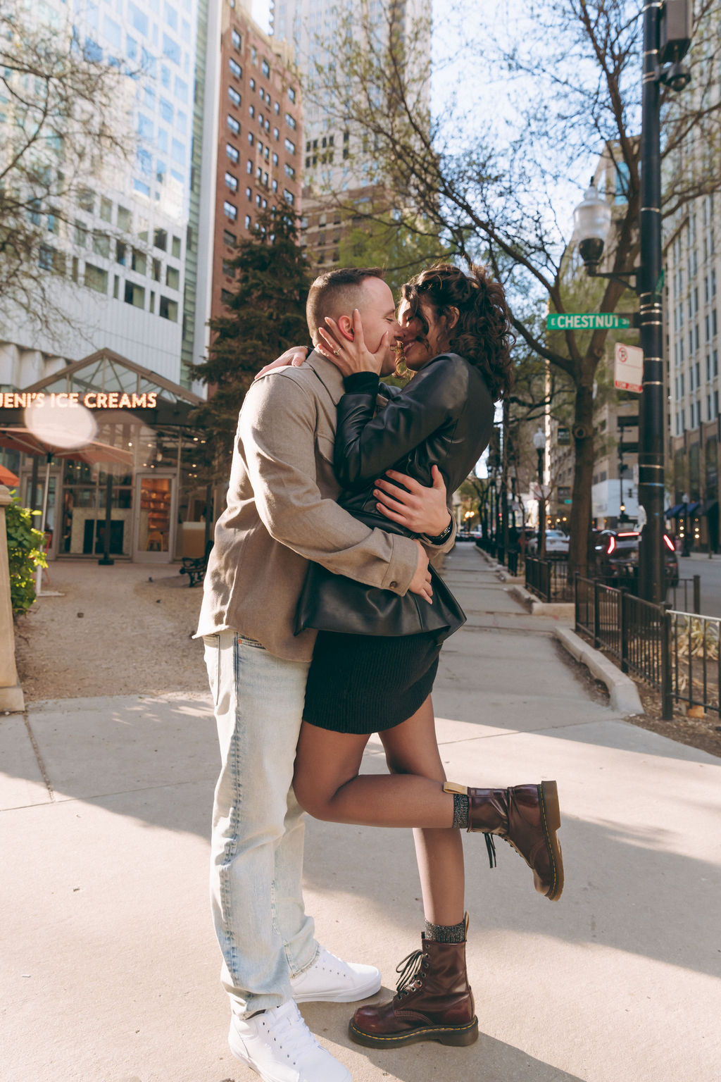 Playful, candid engagement photo in downtown Chicago with couple laughing outside Jeni’s Ice Creams.